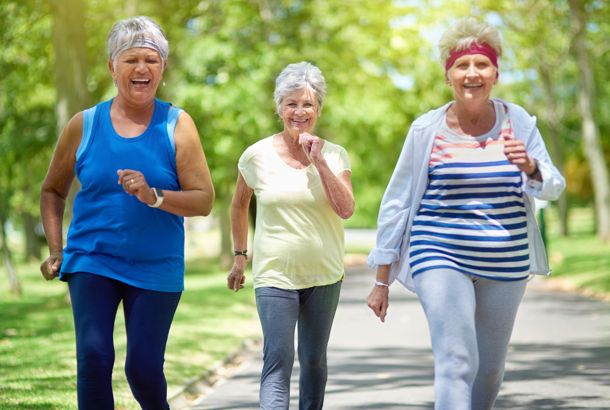 Three senior women jogging together in a serene park, promoting an active and healthy lifestyle.