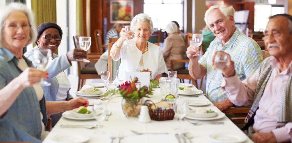 Elderly women eating and talking around a dinner table