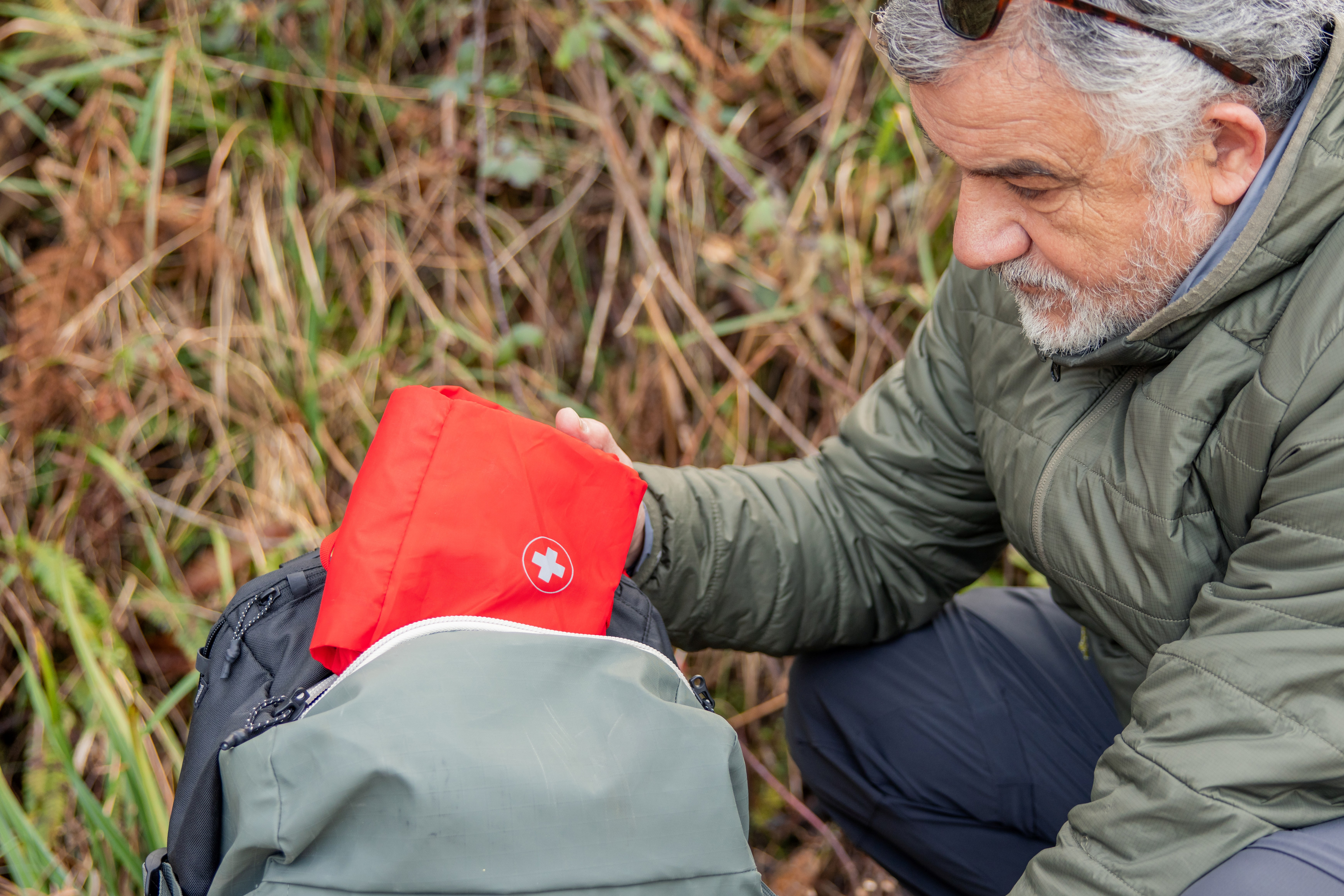 Older adult keeping emergency kit in his backpack.