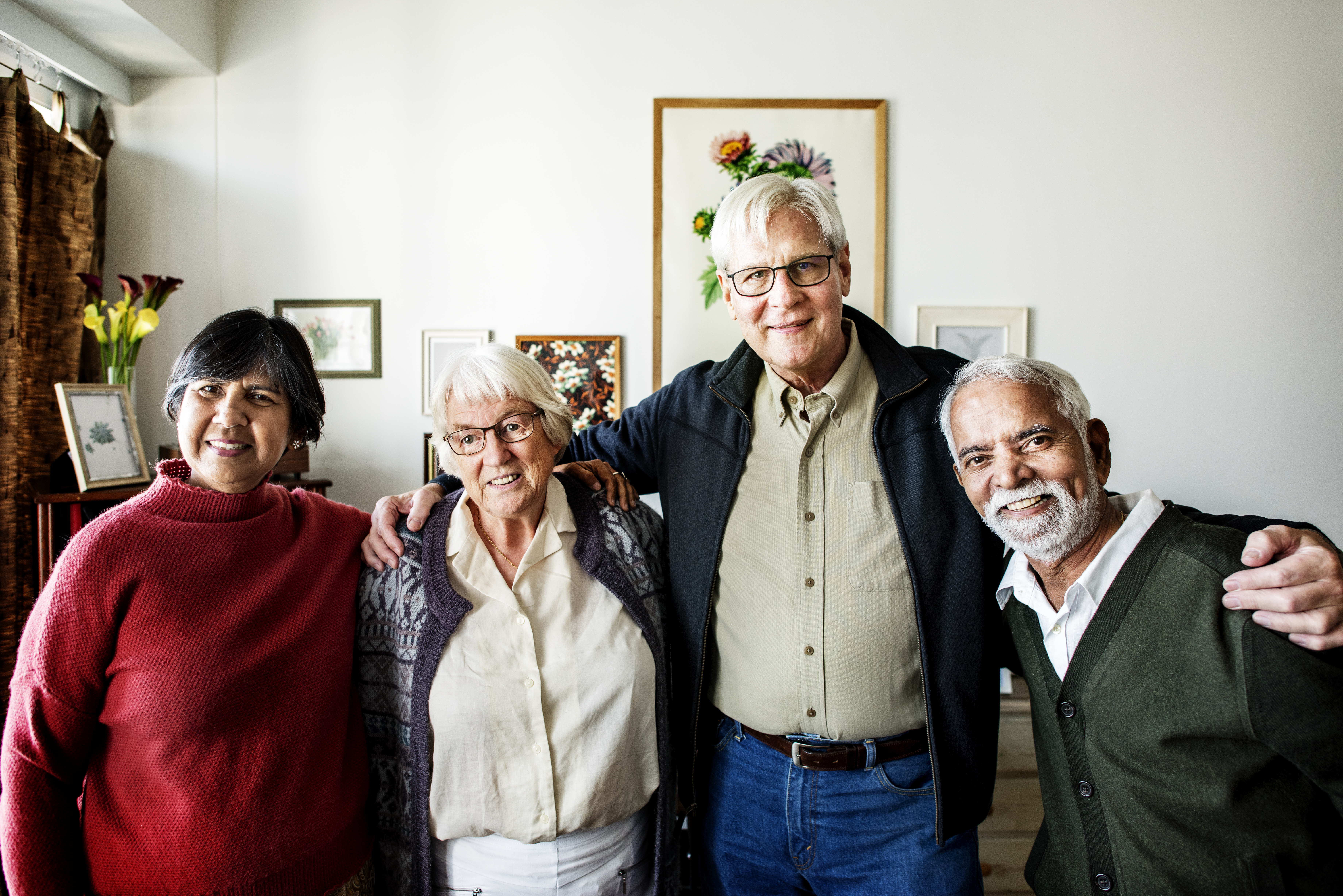 4 older men and woman standing next to each other with arms around each other smiling