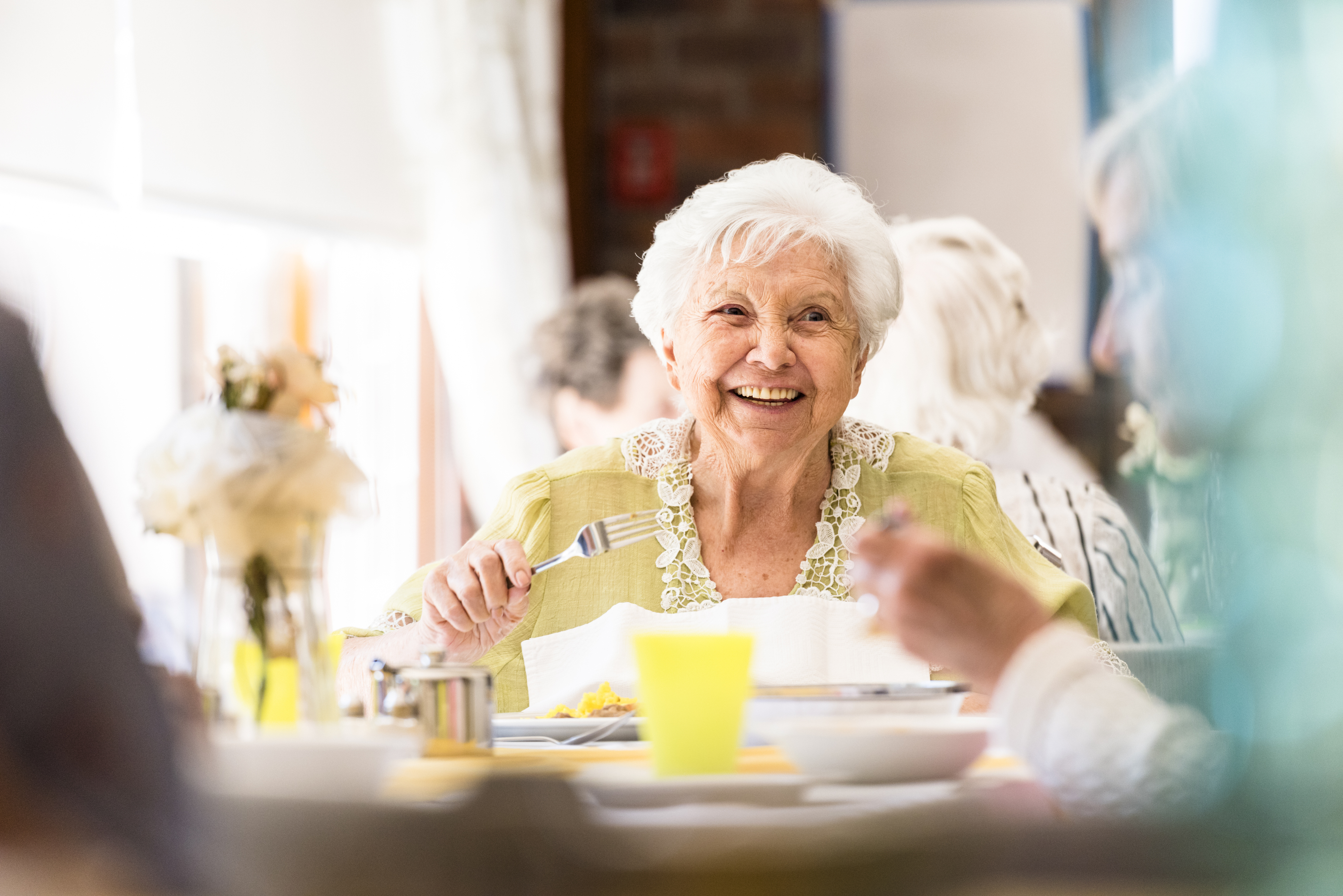 Older adults eating together at a large table, smiling