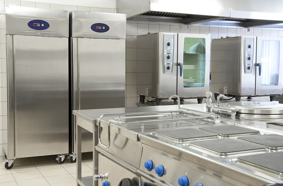 A commercial kitchen featuring stainless steel appliances, including ovens, refrigerators, and countertops, showcasing a professional setup.